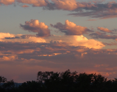 [Atop a long puffy white cloud are two offshoots looking like steam from an ocean liner. The offshoots are purple blue clouds with only a hint of white.]